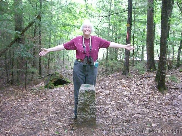 070601ColdRiverCamp_BiStateJill Just beyond the dam, Jill puts one hand in New Hampshire and the other hand in Maine.